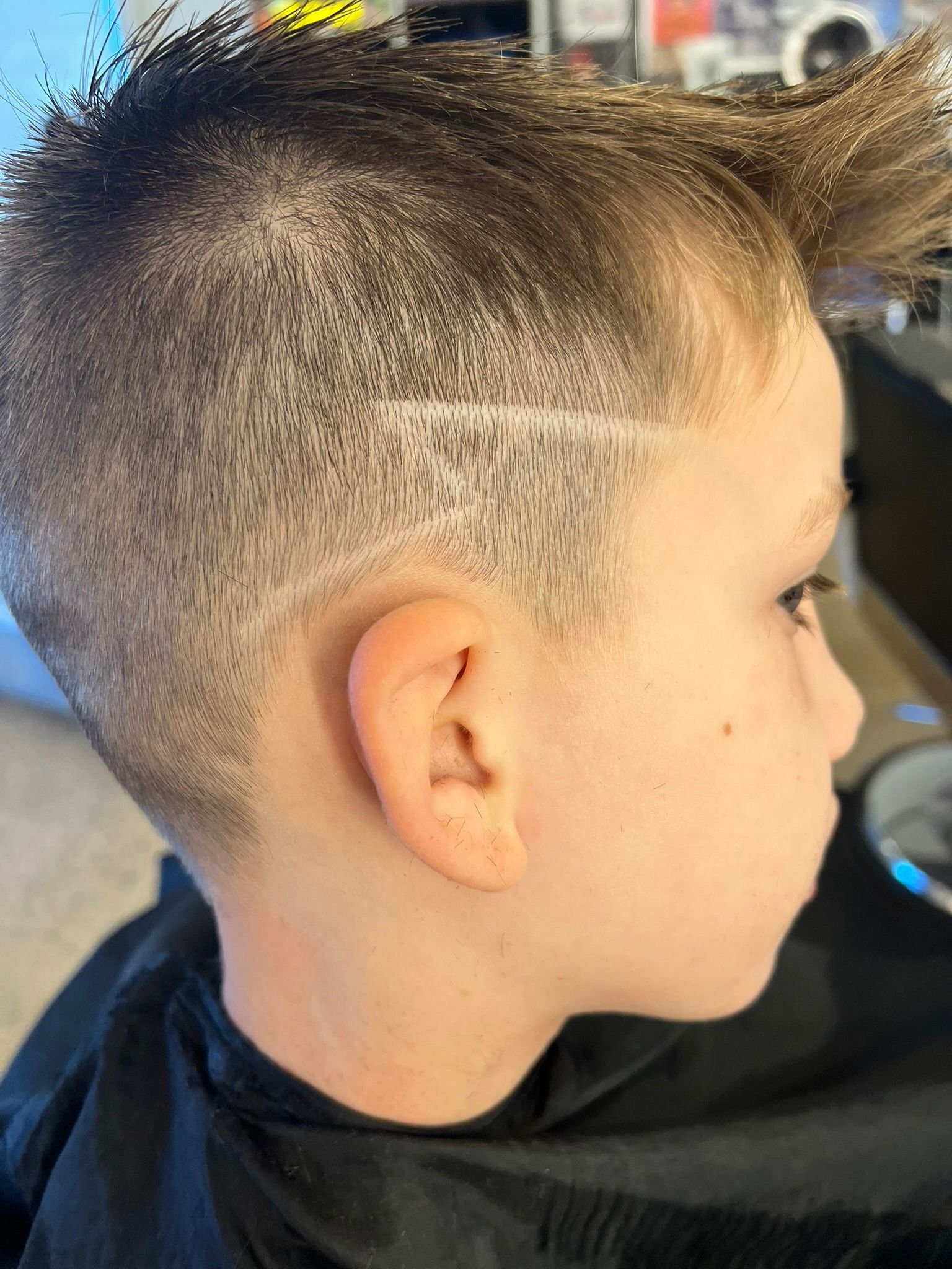 Close faded haircut with a crisp curved line design above the ear