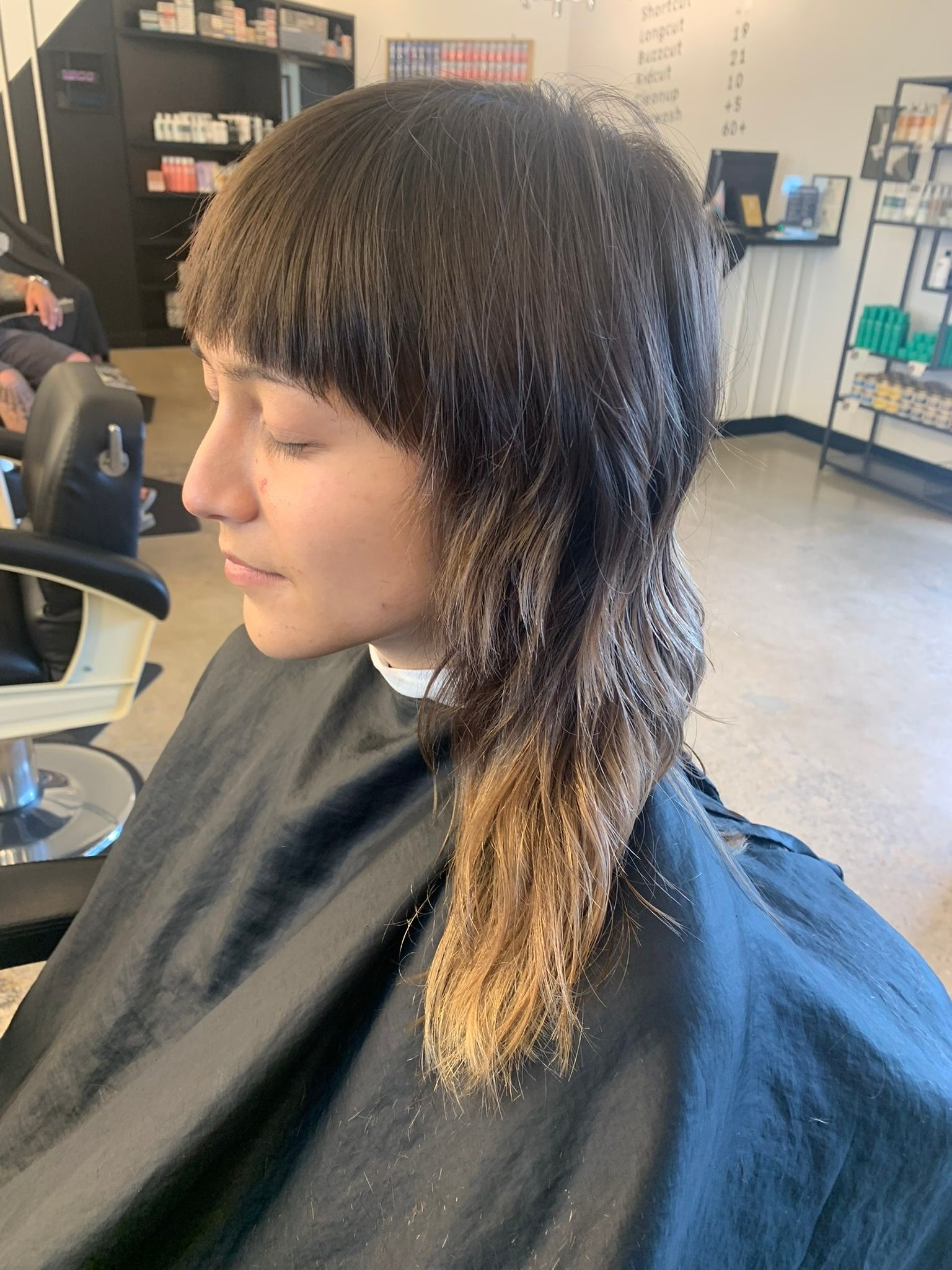 Dark shoulder-length shag with blunt bangs and softly lightened ends