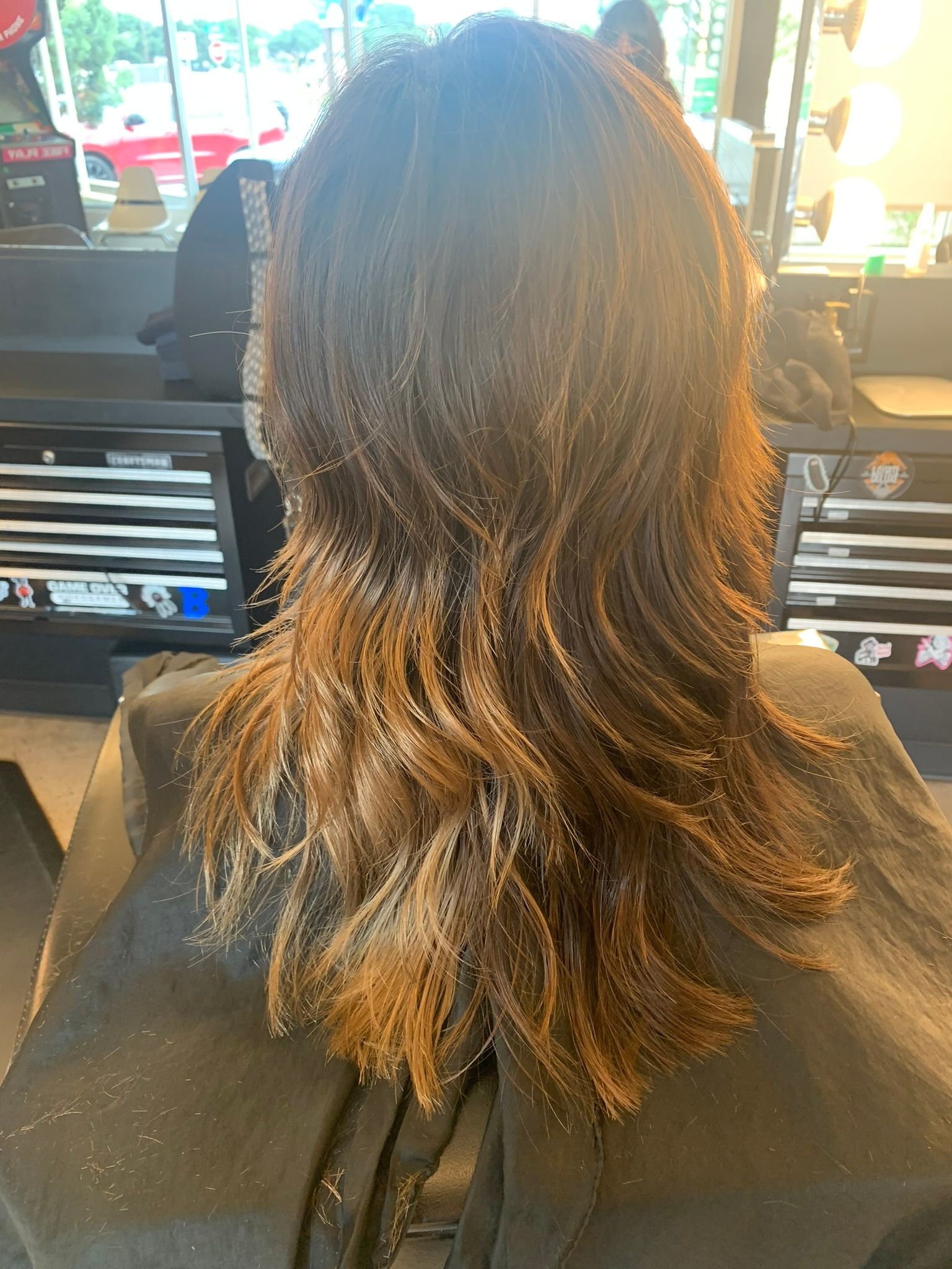 Medium brown layered haircut with warm highlights and feathered ends